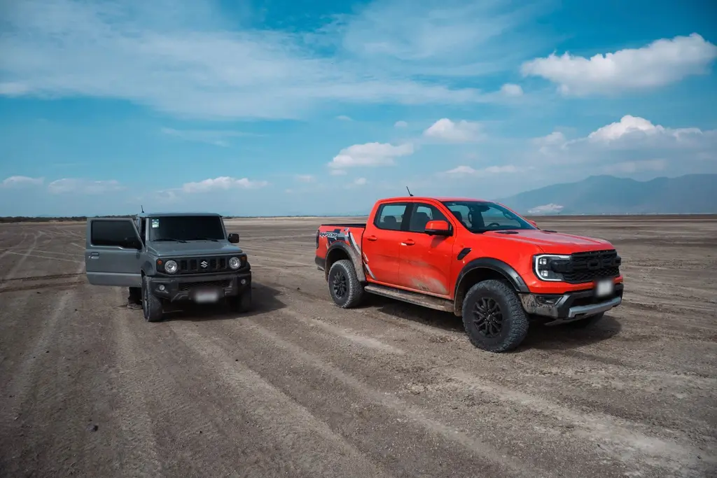 Ranger Raptor Lava Orange junto a un Suzuki Jimny en un llano de tierra